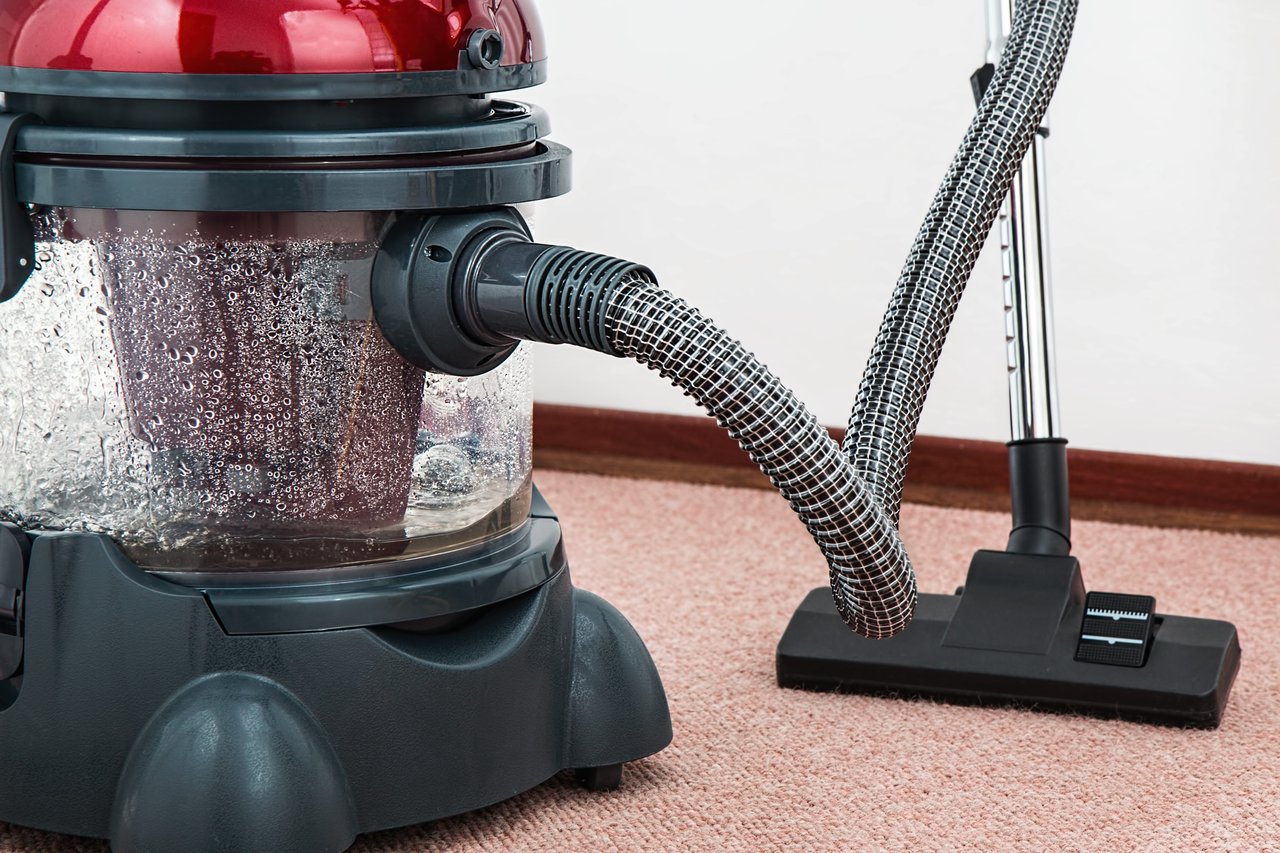 about-02 Close-up of a modern vacuum cleaner with water filtration on carpet floor indoors.
